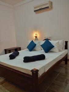 a bed with blue and white pillows on it at Eco Pavilion in Sigiriya