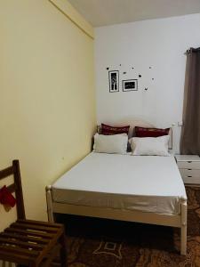 ein Schlafzimmer mit einem weißen Bett und einem Stuhl in der Unterkunft Pensão Simão & Júlia in Órgãos