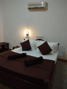 a large bed with brown and white sheets and pillows at Eco Pavilion in Sigiriya