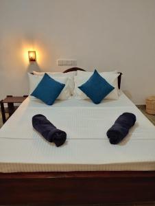 a bed with blue pillows on it with two pillows at Eco Pavilion in Sigiriya