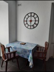 un tavolo e due sedie con un orologio sul muro di Studio côté jardin a Ingersheim