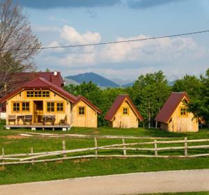 a group of houses in a field with a fence at Maple bungalows in Žabljak