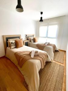 two beds in a room with two windows at Apartamento en palmeira - Colores del Barbanza Naranja in Ribeira