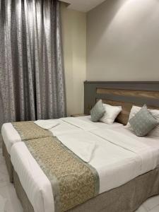 een slaapkamer met een groot bed met witte lakens en kussens bij فندق الروابط نفحات الحرم سابقا in Mekka