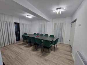 a conference room with a table and green chairs at Pensiunea Elysium in Lunguleţu