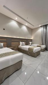 two beds in a large room with white tiles at فندق الروابط نفحات الحرم سابقا in Makkah