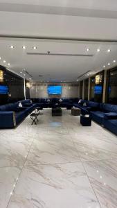 Habitación grande con sofás azules y monitores. en فندق الروابط نفحات الحرم سابقا, en La Meca