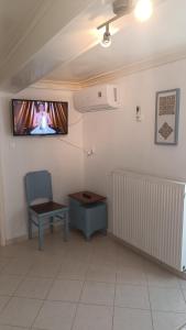Cette chambre dispose d'une télévision, d'une chaise et d'une table. dans l'établissement Το σπιτάκι στον παραδοσιακό οικισμό Λειβαδίων Άνδρου, à Vrakhnós