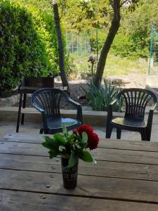 two chairs and a table with a vase of flowers at Gîte 4 "OLIA" aux Magnolias in Aubenas