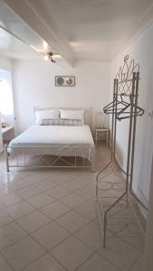 a white bedroom with a bed and a tiled floor at Το σπιτάκι στον παραδοσιακό οικισμό Λειβαδίων Άνδρου in Vrakhnós