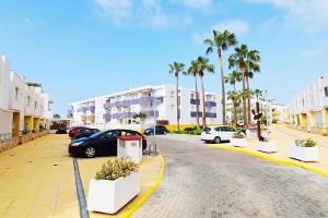 a street with cars parked in a parking lot with palm trees at EXPOHOLIDAYS - Vistas al mar playa ensenada in Almerimar