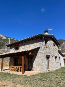 a stone building with a table and chairs in front at Casa de la Mestra, Espinalbet - ALBERGA in Castellar del Riu