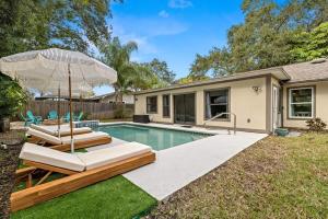 une maison avec une piscine et un parasol dans l'établissement 5 mins to Honeymoon Island~Sand Volleyball~Firepit, à Palm Harbor