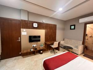una camera con letto, TV e divano di Skymoon Hotel And Restaurant a Indore