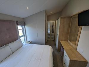 1 dormitorio con 1 cama blanca grande y TV en Morrelo View 24, Cherry Tree Holiday park. en Great Yarmouth