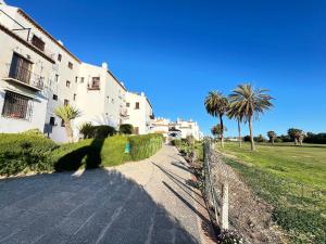 a shadow of a building and palm trees on a path at PUSHE Playa Granada Beach & Golf 24 in Motril