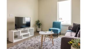 Stunning Nulu 1BR CozySuites 04 في لويزفيل: غرفة معيشة مع تلفزيون وأريكة وطاولة