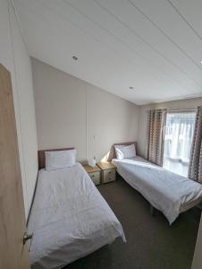 1 dormitorio con 2 camas y ventana en Morrelo View 24, Cherry Tree Holiday park. en Great Yarmouth