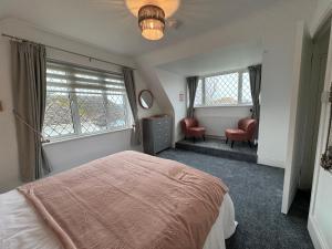 a bedroom with a bed and a chair and windows at Ocean Cottage, Ferring - seaside cottage moments from the beach and Bluebird cafe in Ferring