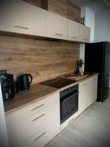 cocina con armarios blancos y nevera negra en Apartament Nowar, en Nowa Ruda
