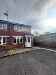 a brick house with a white door and a fence at Cosy 2 bedroomed semi detached house in Brettell Lane