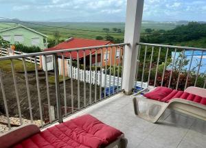 balcón con sofá y vistas a una casa en Villa Ressources, paisible et avec vue dégagée, en Rivière-Salée