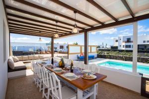 ein Esszimmer mit einem Tisch und einem Pool in der Unterkunft Villa Barrilla - La Vegueta Villas in Tinajo
