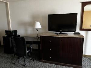 Habitación de hotel con escritorio y tocador con TV. en Budget Inn Laramie, en Laramie