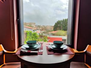 a table with a glass of wine and a window at Guest house Eça Agora! in Vila do Conde