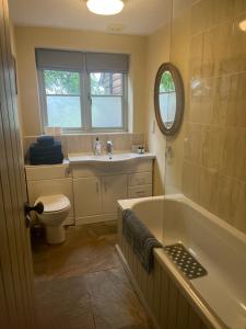 a bathroom with a tub and a sink and a toilet at Elmcroft Holiday Annex in Gillingham +4 photos