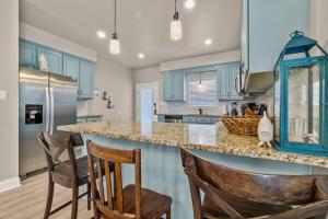 a kitchen with blue cabinets and a counter with chairs at Big Blue Cottage 2A in Gulf Shores