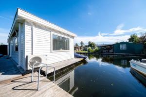 ein Haus auf einem Dock neben einem Wasserkörper in der Unterkunft New- Private Cosy Houseboat, on a lake near Amsterdam in Vinkeveen