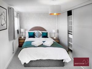 a bedroom with a large bed with blue pillows at Jennett's Park, Bracknell - 2 Bedroom Home in Bracknell