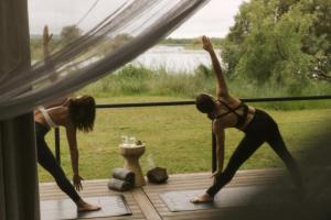 a man and a woman doing yoga in a window at Zambezi Sands by Batoka in Victoria Falls