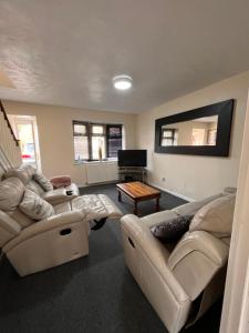 een woonkamer met 2 banken en een tafel bij Cosy 2 bedroomed semi detached house in Brettell Lane