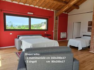 2 Betten in einem Zimmer mit roter Wand in der Unterkunft Casa Maria in Magliano in Toscana