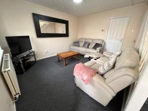 a living room with two couches and a television at Cosy 2 bedroomed semi detached house in Brettell Lane +6 photos