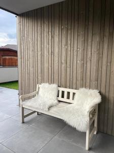 un banc blanc avec des coussins en bois assis sur une terrasse dans l'établissement Apartment Malfi, à Fiè