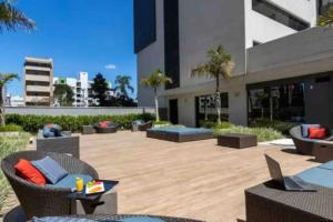 a patio with chairs and tables and a building at THE ONE - Flat Batel Premium in Curitiba
