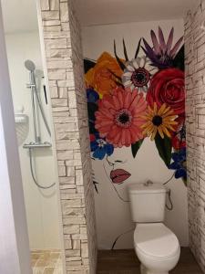 a bathroom with a flower mural above a toilet at Un été sans fin in Lauris
