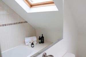 ein Badezimmer mit einem Dachfenster und Flaschen Wein auf einem Regal in der Unterkunft Beautiful Oxford Townhouse near City Centre in Oxford
