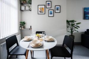 - une table à manger blanche avec des chaises noires et une table blanche avec de la vaisselle dans l'établissement Belfast Townhouse, à Belfast 12 autres photos