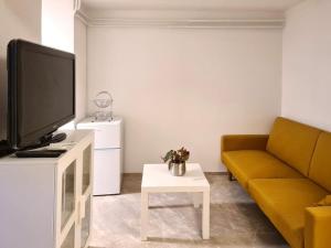 a living room with a yellow couch and a tv at Cozy apartment under the vine in Sežana