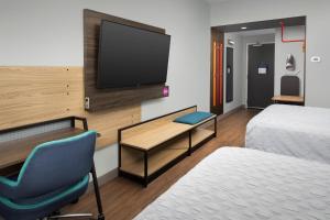 a hotel room with a tv and a bed and a chair at Tru By Hilton Jacksonville Airport in Jacksonville