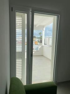 una camera con due porte scorrevoli in vetro e una sedia verde di Appartamento Rione Aia a Carmiano