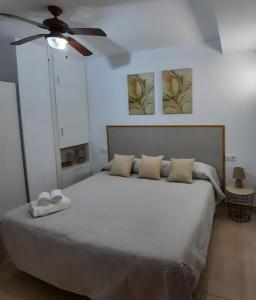 a bedroom with a white bed with a ceiling fan at TRANQUILO APARTAMENTO ZONA CENTRO in Alcalá de Guadaira