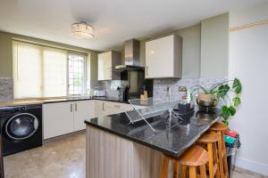 a kitchen with white cabinets and a black counter top at Captivating 3-Bed House in Saffron Walden in Saffron Walden