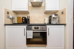 a kitchen with white cabinets and a counter top at Deluxe 1 Bed Versace HotTub SkyTV in Saffron Walden