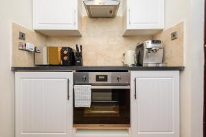 a kitchen with white cabinets and a counter top at Deluxe 1 Bed Flat Hot Tub Sky Tv in Saffron Walden