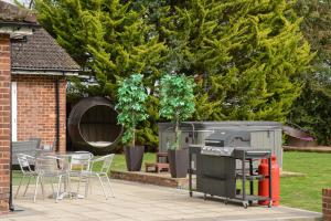 a patio with a grill and a table and chairs at Deluxe 1 Bed Flat Hot Tub Sky Tv in Saffron Walden